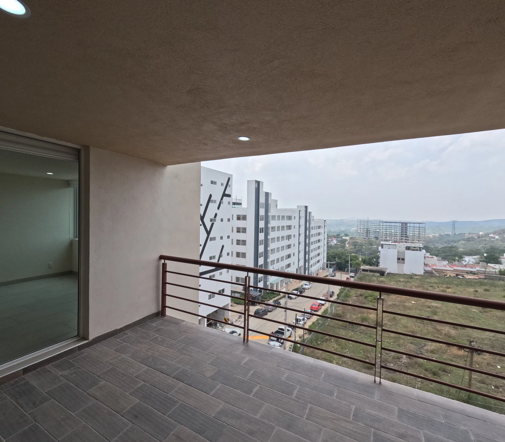 Balcon de departamento con vista a la fachada del edificio contiguo y al entorno urbano de Jilotzingo.