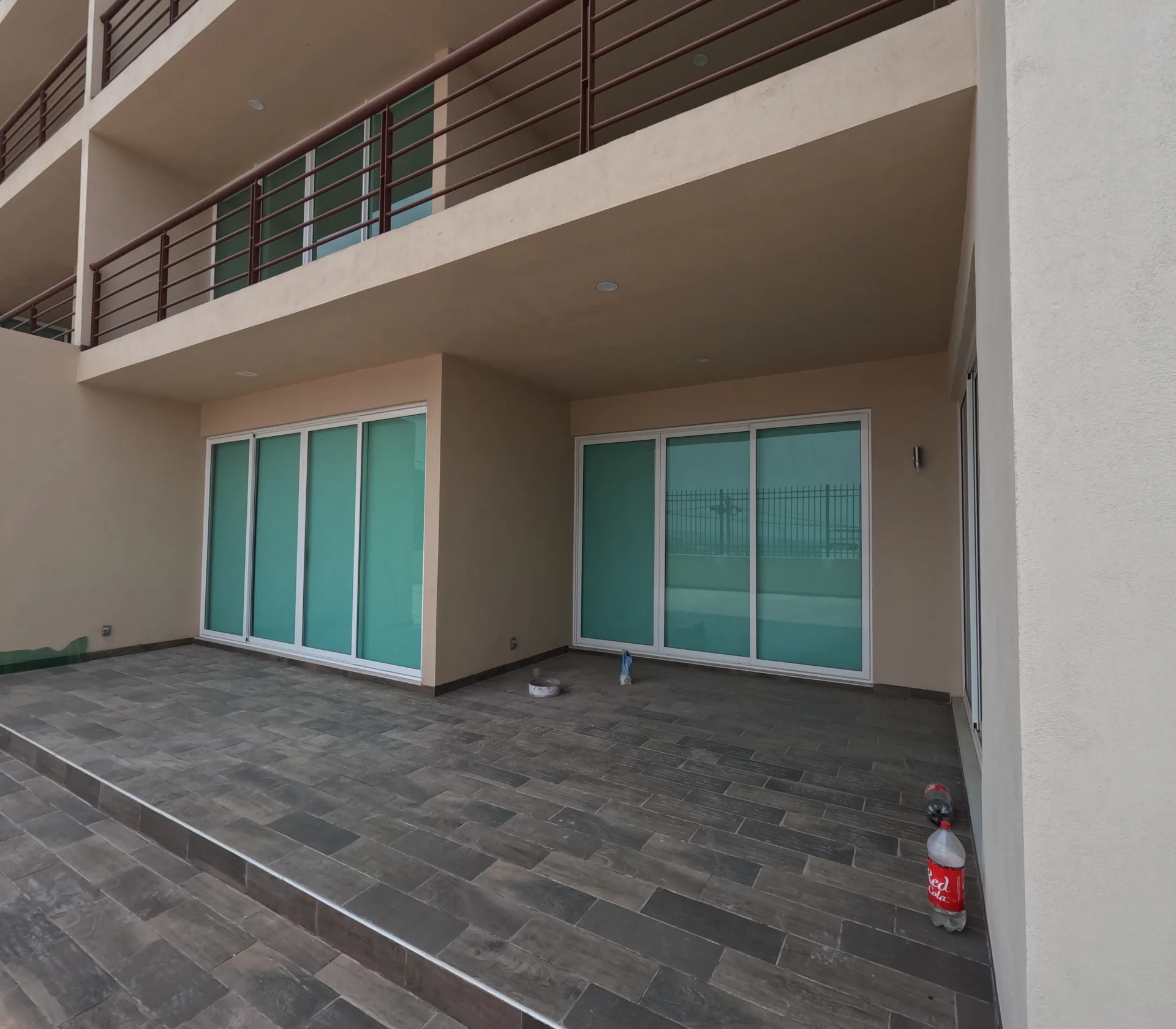 Terraza de departamento con vista hacia la fachada interior del edificio Residencial El Fraile, con vidrios verdes y barandales metalicos.