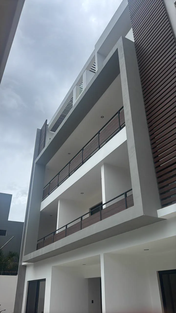 Fachada exterior de Itzae: balcones de tres niveles con barandales de madera y fachada blanca, vista hacia el patio interior.